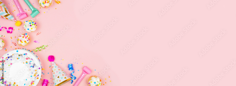 Birthday party corner border on a pastel pink banner background. Overhead view with cakes, party hats and confetti. Copy space. Birthday party corner border on a pastel pink banner background. Overhead view with cakes, party hats and confetti. Copy space.