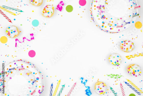 Birthday party frame on a white background. Top view with cakes, candles and confetti. Copy space.
