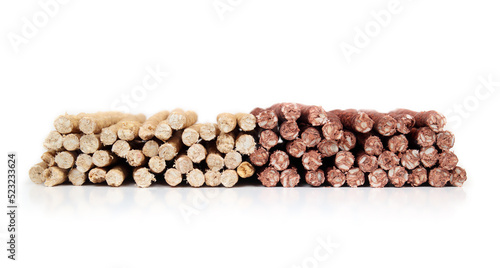 Many rawhide chew sticks for dogs  front view. Large amount of chicken and beef flavoured sticks stacked. Dental health treats for dogs and behavioral enrichment. Selective focus. White Background.