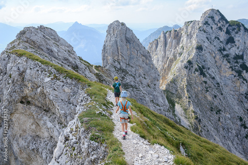 Two children walk a stale ridge in rocky terrain