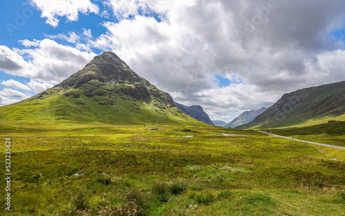 The A82 road crosses pasture fields in the valley floor of Glen Coe. The A82 road crosses pasture fields in the valley floor of Glen Coe  under the mountains of the West Highlands of Scotland.