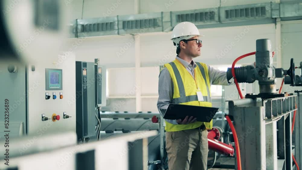 Wastewater operator inspecting a sewage cleaning system using a laptop
