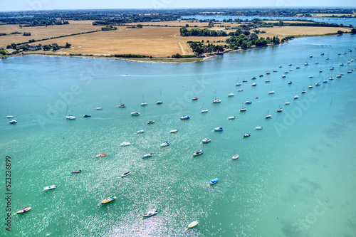 Bosham estuary full of boats with Motorboats and Sailing boats navigating between them while the water sparkles with the reflection of the sun, Aerial photo. photo
