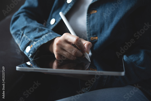 Close up of woman hand holding and using stylus pen writing or drawing on digital tablet pc via mobile app during working at home