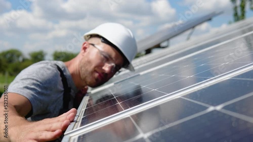 Close up of an young engineer hand is checking an operation of sun and cleanliness of photovoltaic solar panels on a sunset. Green electricity and alternative energy ecological concept