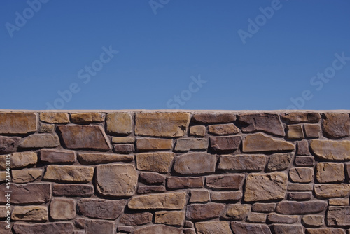 Partial close-up view of an old stone wall and blue sky