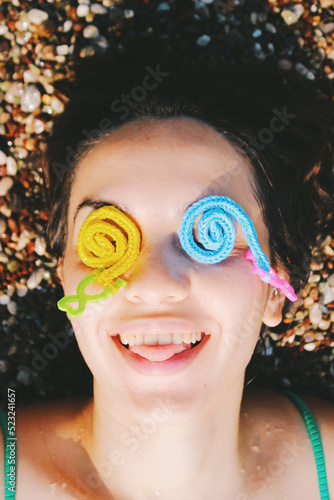 funny portrait of young woman smiling with childs toy on her eyes in beach at summertime