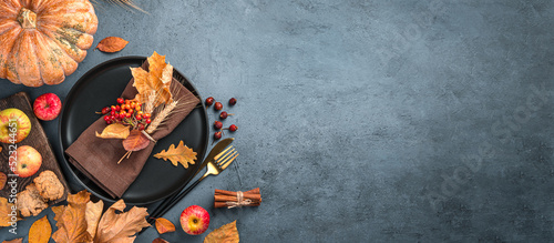 Autumn background with a plate with cutlery on a graphite background. Top view, copy space