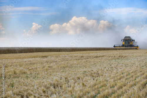 Combine harvesters with grain header, wide chaff spreader reaping cereal ears.