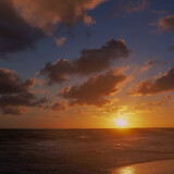 A beautiful sunrise on the ocean, the scarlet color of the sky, clouds, a romantic moment on the beach