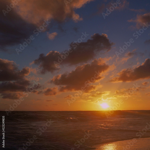 A beautiful sunrise on the ocean, the scarlet color of the sky, clouds, a romantic moment on the beach © Ulia Koltyrina