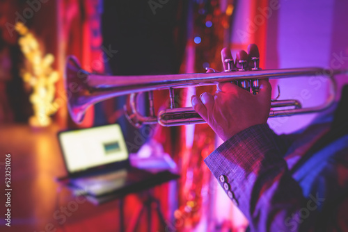 Concert view of a male trumpeter, professional trumpet player with vocalist and musical during jazz band performing in the background