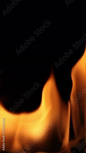 Vertical video of fire flames flickering with black background.
