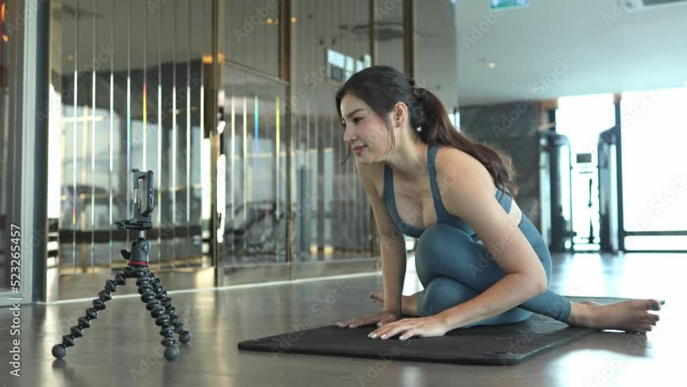 Beautiful young asian woman Greeting her followers in front of the camera on their smartphone while live streaming at the gym. Beautiful young asian woman Greeting her followers in front of the camera Beautiful young asian woman Greeting her followers in front of the camera on their smartphone while live streaming at the gym. Beautiful young asian woman Greeting her followers in front of the camera