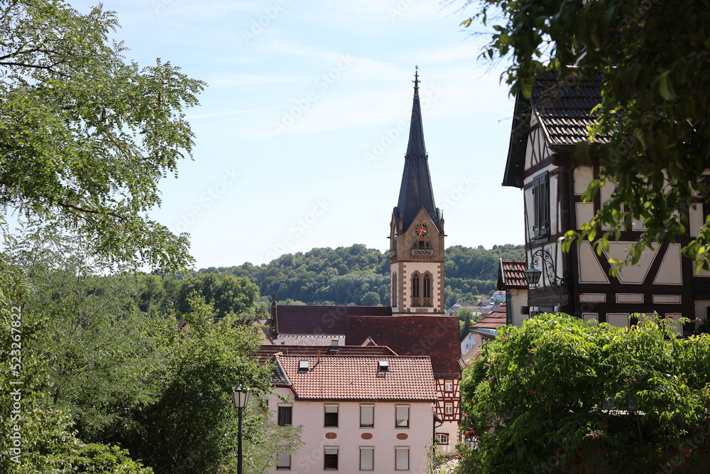 Catholic medieval church in european city, view of the fachwerk houses, tiled roofs and old church in summer