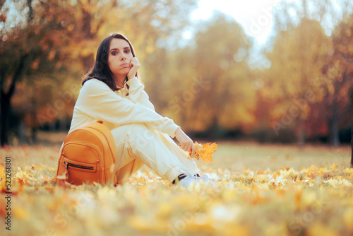 Sad Woman Sitting in the Park Resting Feeling Nostalgic. Unhappy melancholic person sitting on the ground in autumn season photo