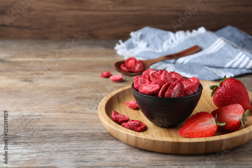 Freeze dried and fresh strawberries on wooden table. Space for text