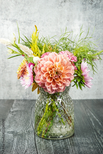 Beautiful bouquet of summer flowers in a green glass vase. Black table, gray background. Dahlias, celosia, cosmos, and aster flowers. © Kathy