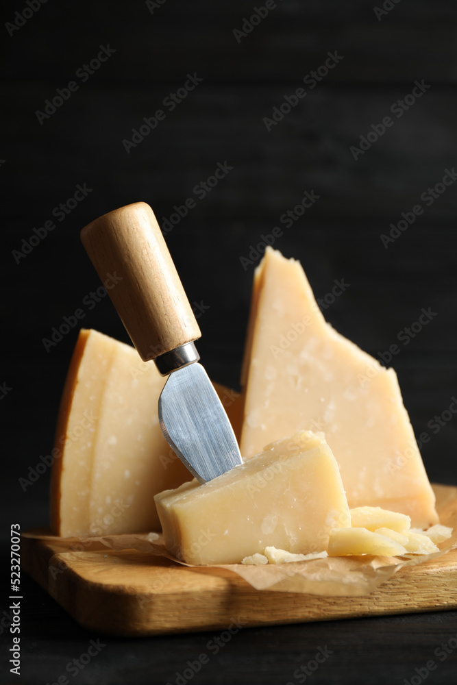 Fototapeta premium Pieces of Parmesan cheese and knife on black wooden table