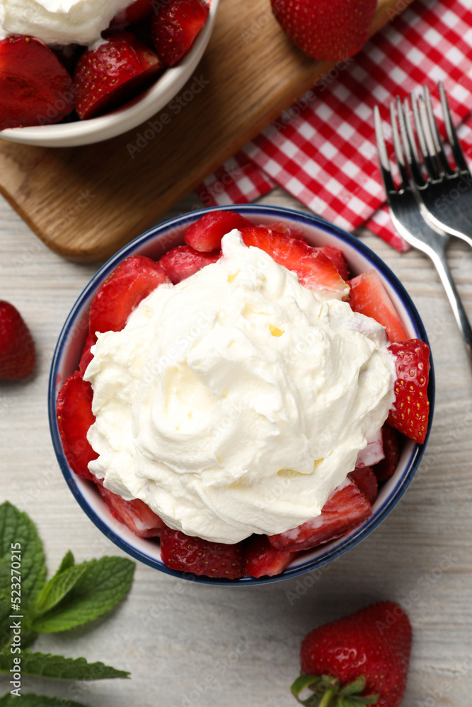Delicious strawberries with whipped cream served on wooden table, flat lay Delicious strawberries with whipped cream served on wooden table, flat lay