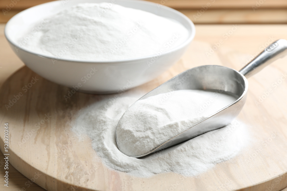 Baking soda in scoop and bowl on wooden table Baking soda in scoop and bowl on wooden table