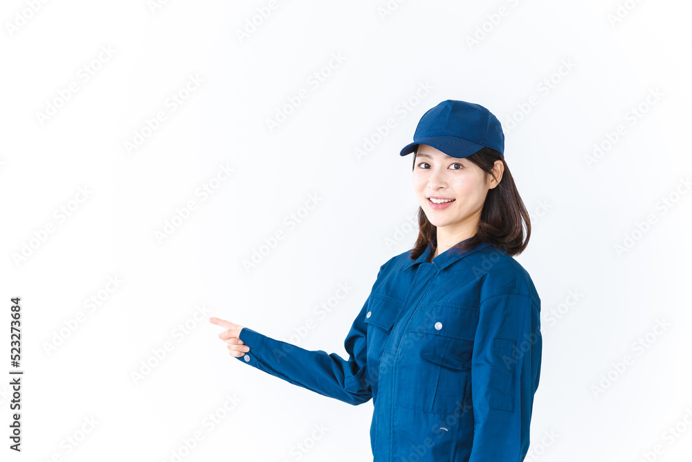 作業服を着て笑顔で指差す若い女性