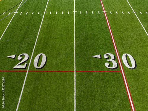 Aerial image of a typical synthetic turf football field 20 yard and 30 yard line in white. 