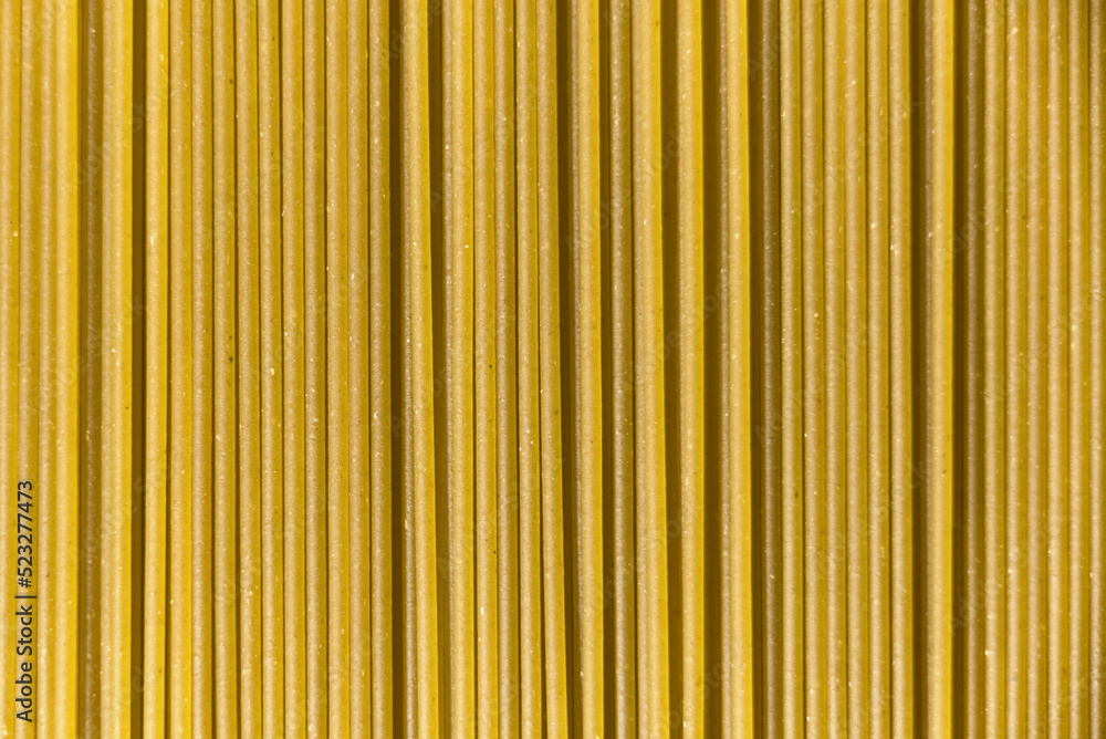 Obraz premium Italian healthy food background, raw spinach spaghetti filling the frame in a textured design of green vertical pasta lines.