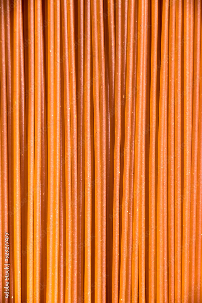 Italian healthy food background, raw sweet bell pepper spaghetti filling the frame in a textured design of red vertical pasta lines. Italian healthy food background, raw sweet bell pepper spaghetti filling the frame in a textured design of red vertical pasta lines.