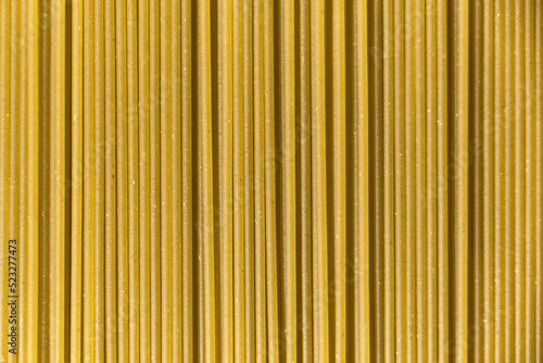 Italian healthy food background, raw spinach spaghetti filling the frame in a textured design of green vertical pasta lines.