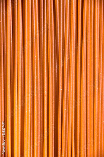 Italian healthy food background, raw sweet bell pepper spaghetti filling the frame in a textured design of red vertical pasta lines.