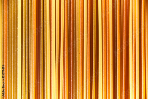 Abstract italian food background, raw colourful vegetable spaghetti filling the frame in a textured design of mixed colors vertical pasta lines.