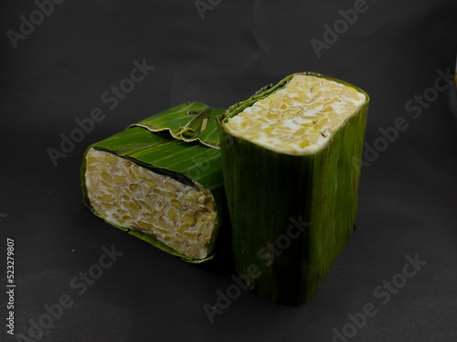 Photo of two blocks of raw tempeh wrapped in banana leaves and isolated on a black background in the Cikancung area - Indonesia. Not Focus photo