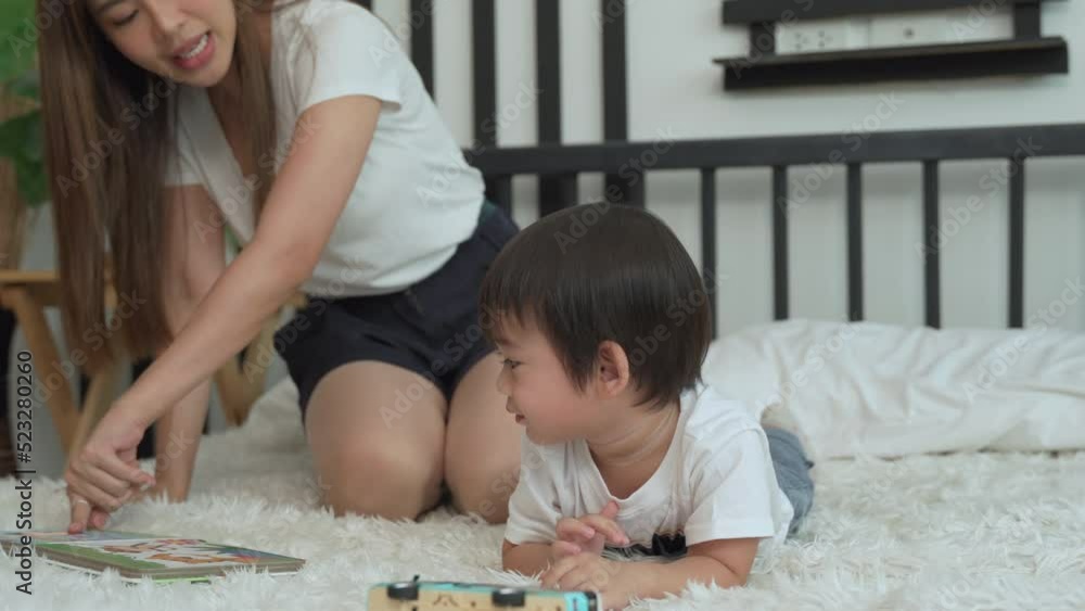 Asian young mother raising a little son she is promoting her son development with an animal cartoon book in the bedroom at house. Asian young mother raising a little son she is promoting her son development with an animal cartoon book in the bedroom at house.