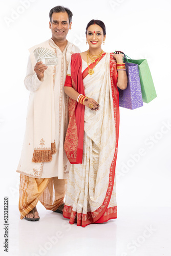 Bengali family in traditional clothing holding 500 rupees banknotes and shooping bag 