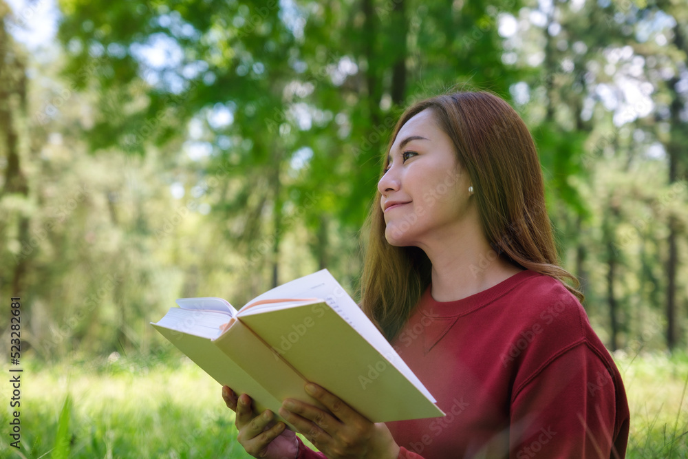 Portrait of a beautiful young asian woman reading a book while sitting in the park Portrait of a beautiful young asian woman reading a book while sitting in the park