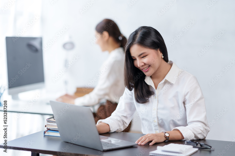 Beautiful Asian businesswoman working on a desk with a laptop while looking at the documents received in the office. Beautiful Asian businesswoman working on a desk with a laptop while looking at the documents received in the office.