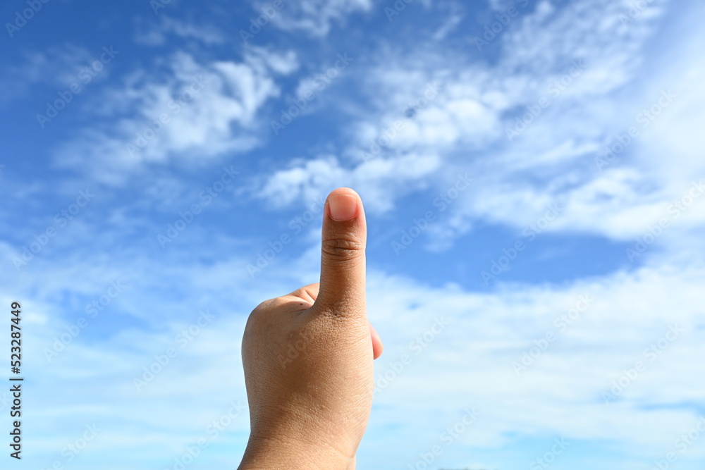 woman's hand showing thumbs up with cloudy blue sky in the background woman's hand showing thumbs up with cloudy blue sky in the background