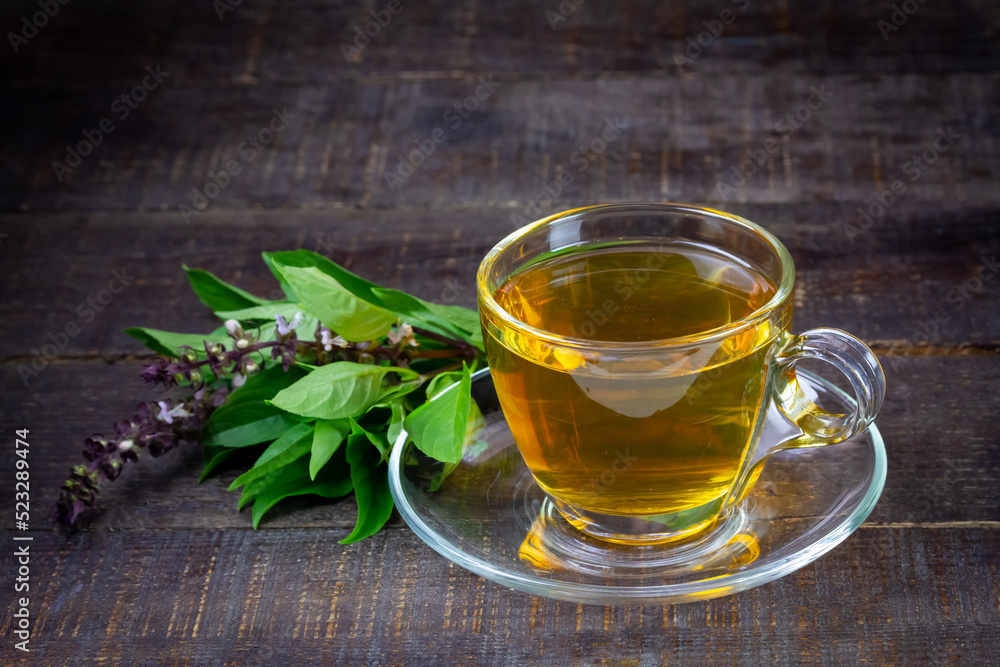 Basil tea in transparent cup with green leaf on rustic wooden table. Basil is food and herb for healthy.