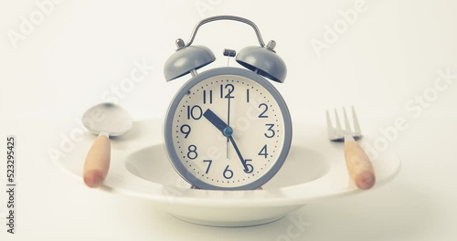 Time to lose weight , intermittent fasting eating control or time to diet concept , alarm clock with dish and spoon  decoration on a white background