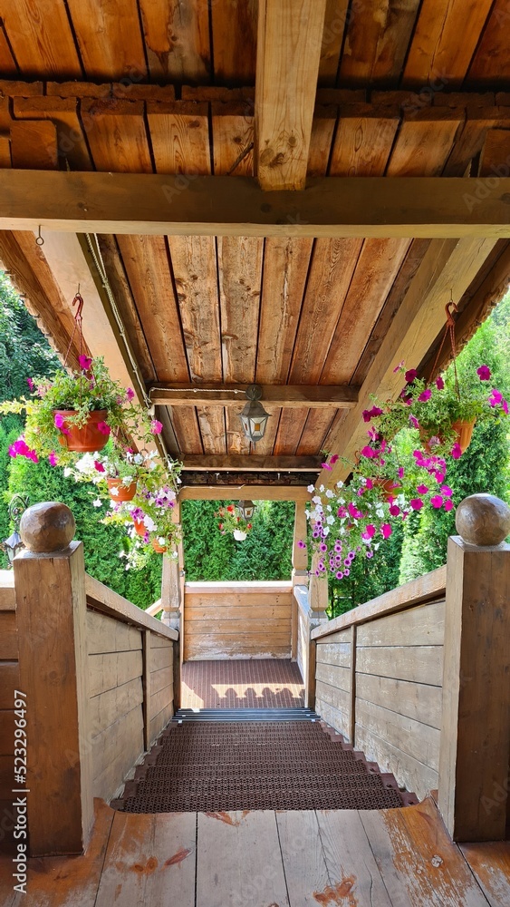 Wide wooden staircase with roof is decorated with many colorful summer flowers