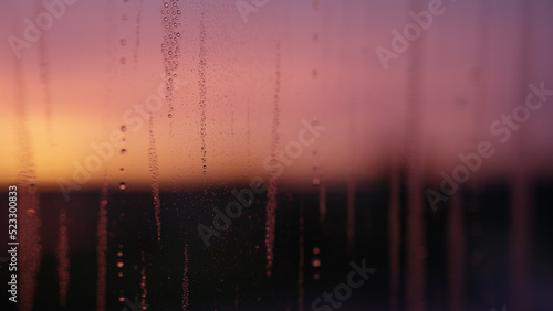 Water drops on window glass with sunset light