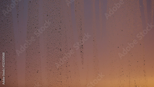 Water drops on window glass with sunset light