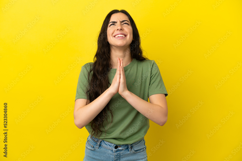 Young caucasian woman isolated on yellow background keeps palm together. Person asks for something Young caucasian woman isolated on yellow background keeps palm together. Person asks for something