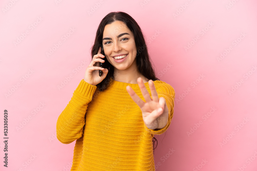Young caucasian woman using mobile phone isolated on pink background happy and counting three with fingers Young caucasian woman using mobile phone isolated on pink background happy and counting three with fingers