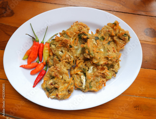 Bala-bala or Bakwan or vegetable fritter, traditional Indonesian snack, made from carrot, cabbage and bean sprouts and mix with flour and deep fried. Served with chillies and peanuts sauce