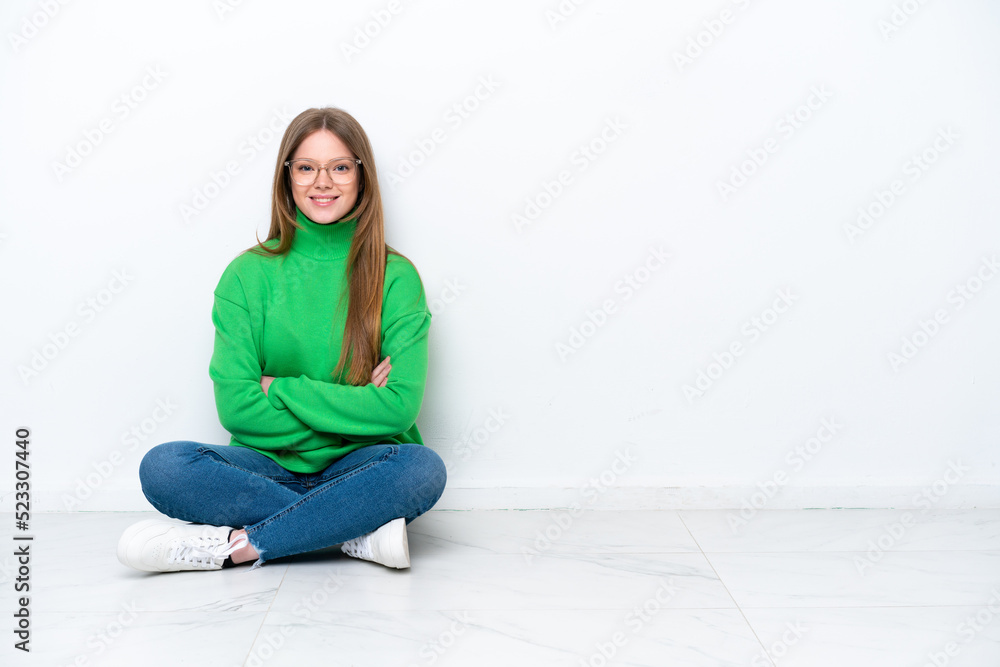 Young caucasian woman sitting on the floor isolated on white background keeping the arms crossed in frontal position Young caucasian woman sitting on the floor isolated on white background keeping the arms crossed in frontal position