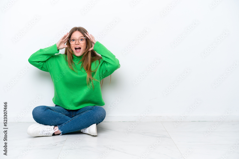 Young caucasian woman sitting on the floor isolated on white background with surprise expression Young caucasian woman sitting on the floor isolated on white background with surprise expression