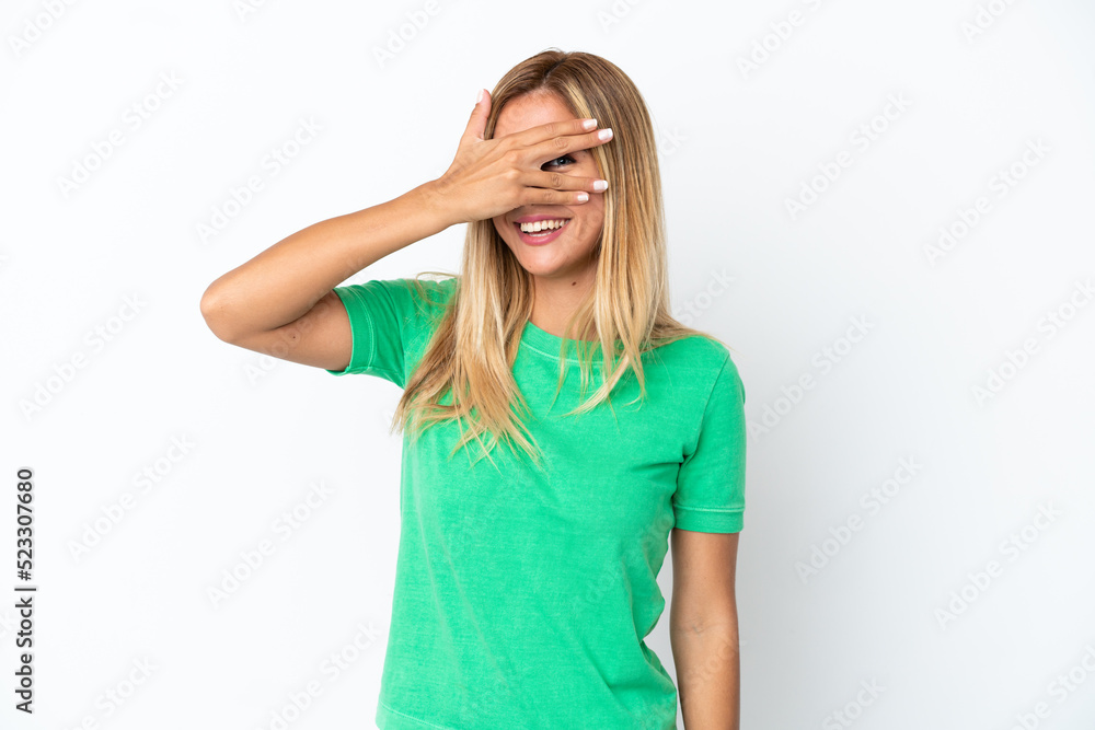 Blonde Uruguayan girl isolated on white background covering eyes by hands and smiling Blonde Uruguayan girl isolated on white background covering eyes by hands and smiling