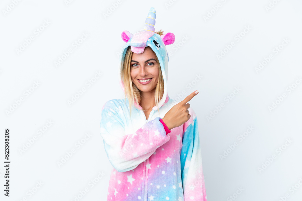 Blonde Uruguayan girl wearing a unicorn pajama isolated on white background pointing to the side to present a product Blonde Uruguayan girl wearing a unicorn pajama isolated on white background pointing to the side to present a product